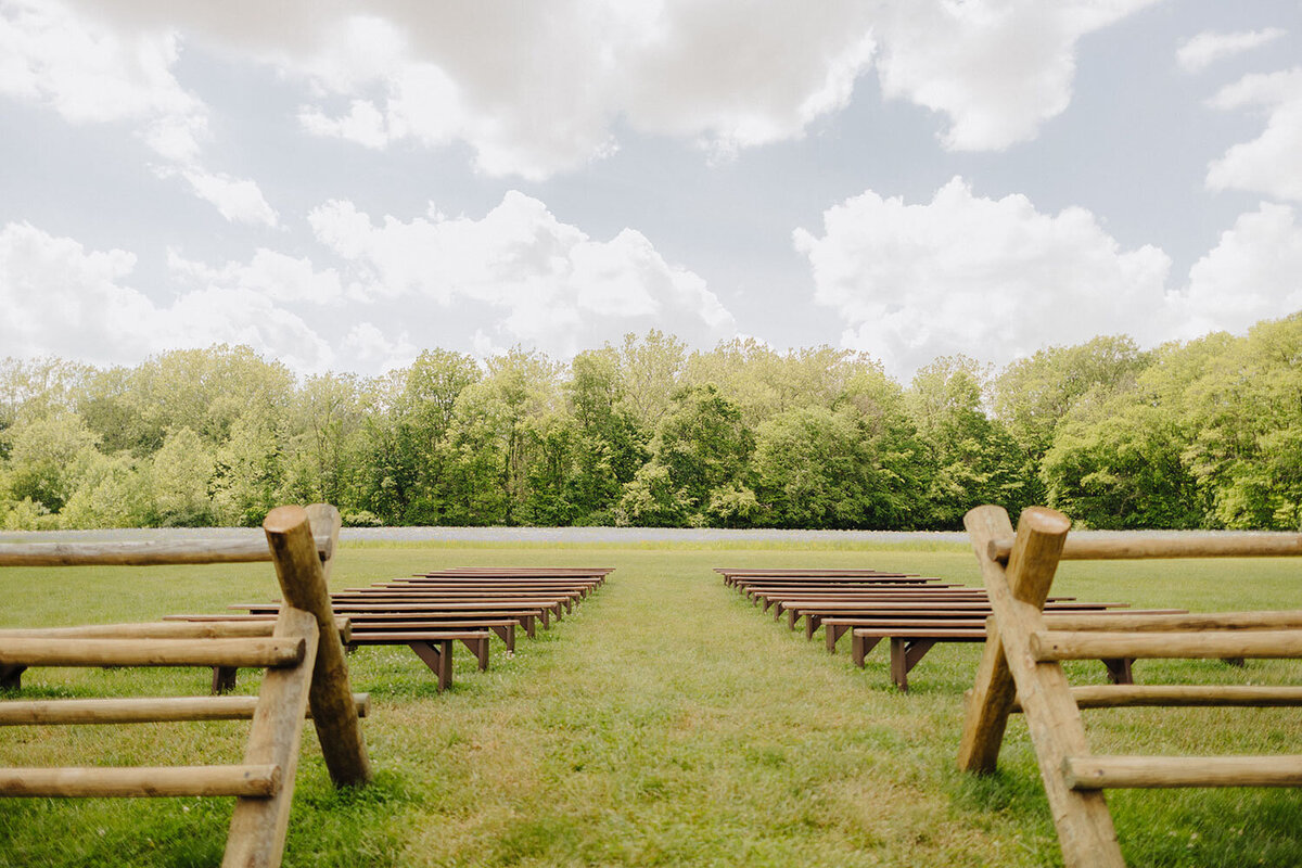 Outdoor ceremony seating arranged with a scenic field and trees in the background