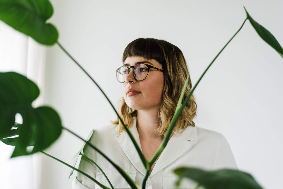 Woman wearing glasses with monsterra plant.