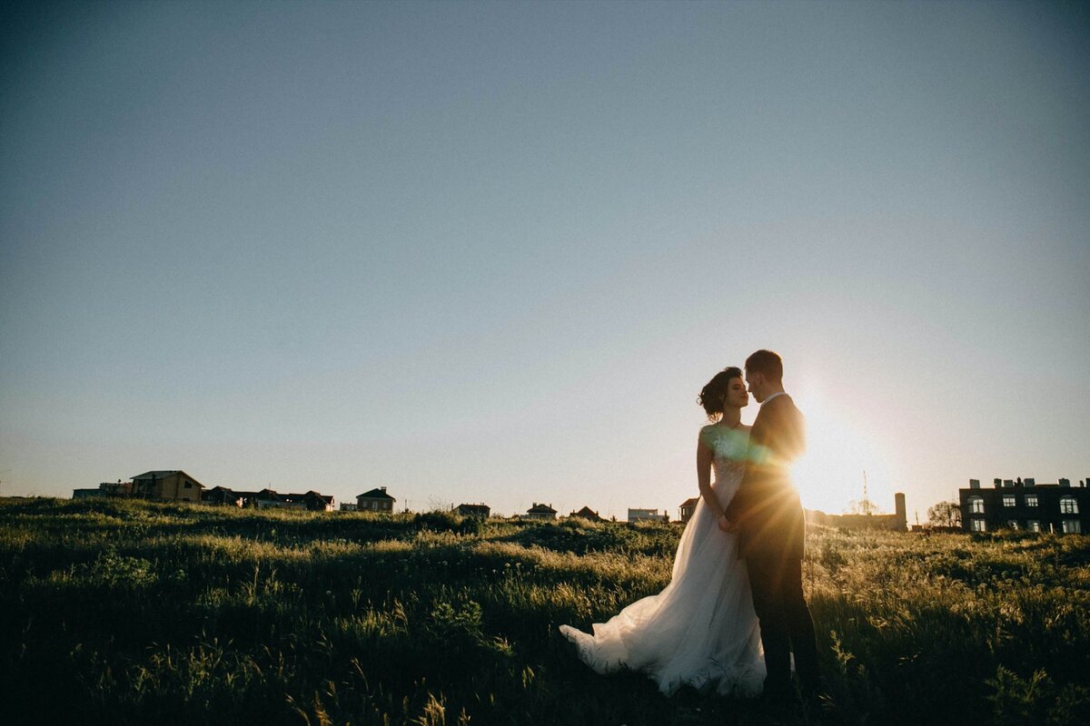 A wedding couple about to kiss standing in front of the setting sun