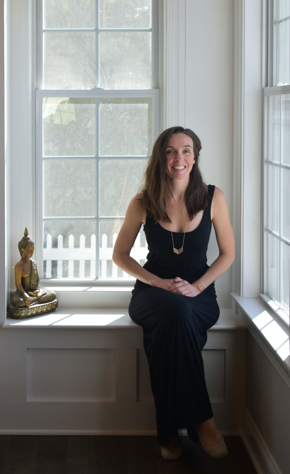 Christine Camarda seated in front of window with buddha, books, vases, photographs and other decor items as inspiration