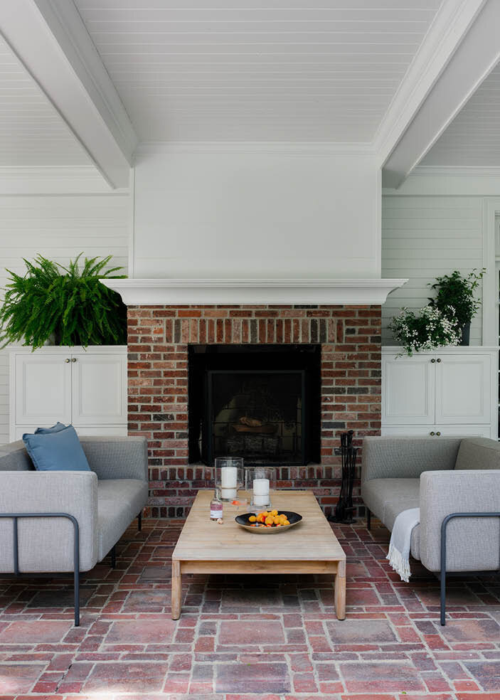 The covered patio at the Concord estate features a cozy fireplace, cool sofas, and a low, wide teak coffee table from Design Within Reach for ultimate relaxation.