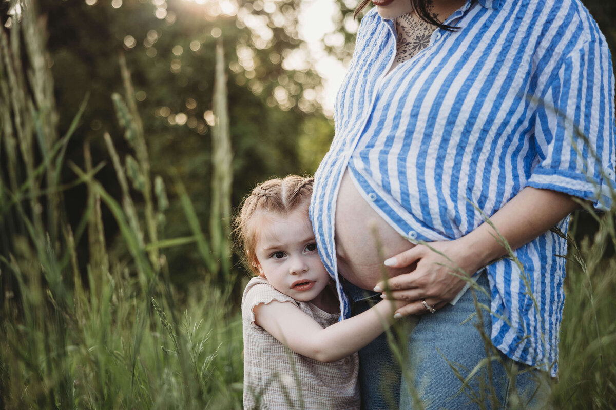 little girl hugging moms pregnant belly in portrait session with reva davis photography