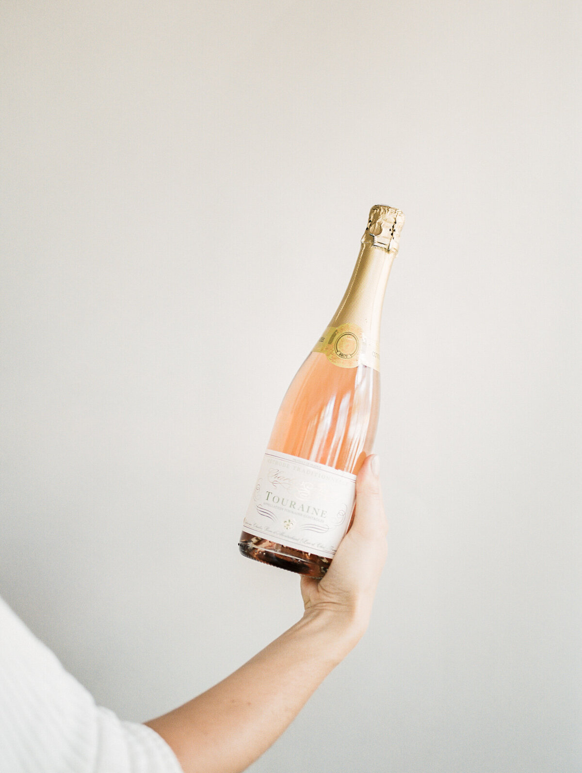 woman holds champagne bottle with light background, film brand photographer in Michigan