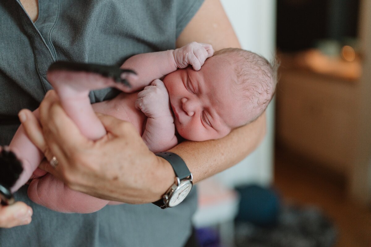 midwife holding brand new baby doing newborn check