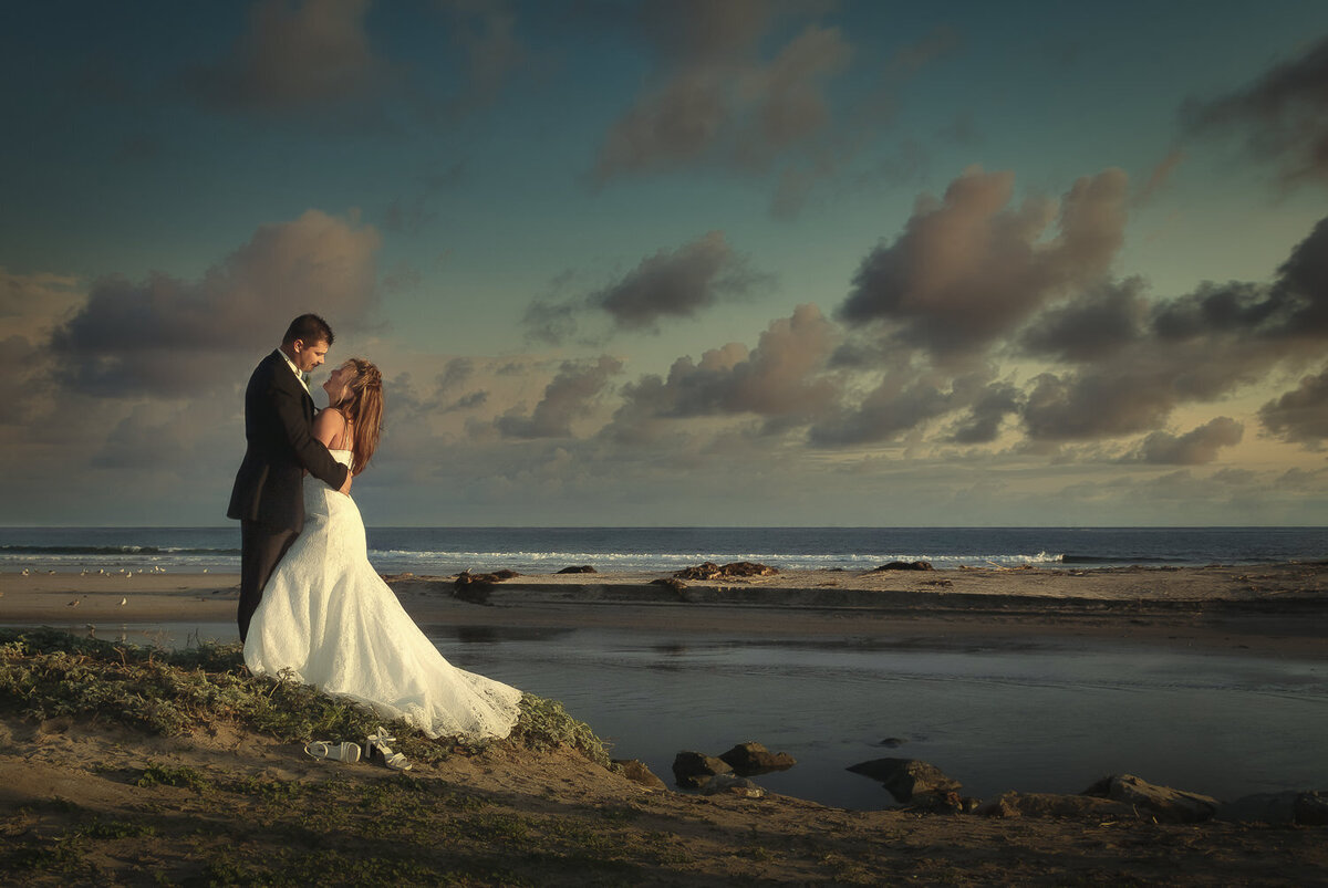 Bride and groom embrace by the seaside on their wedding day
