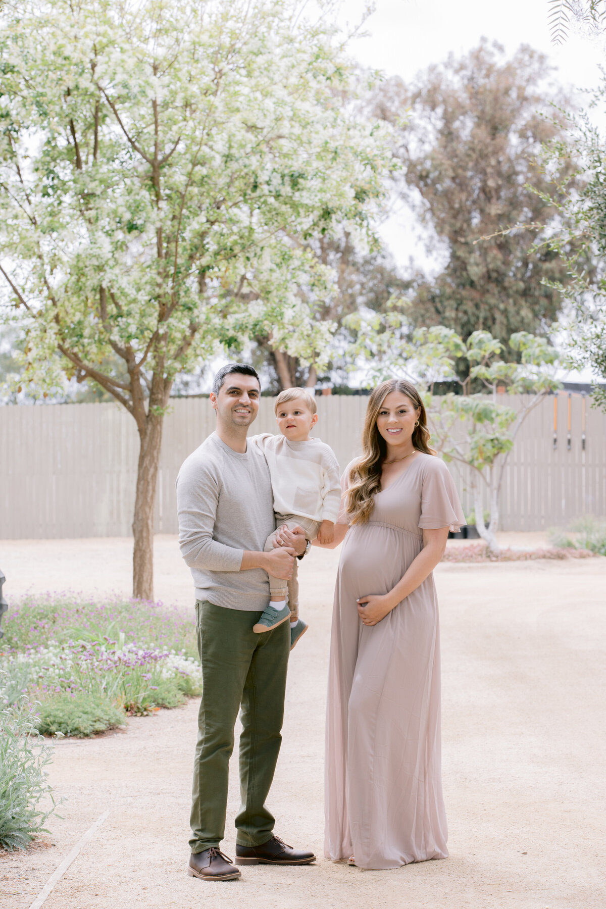 Two parents smiling as one holds a toddler