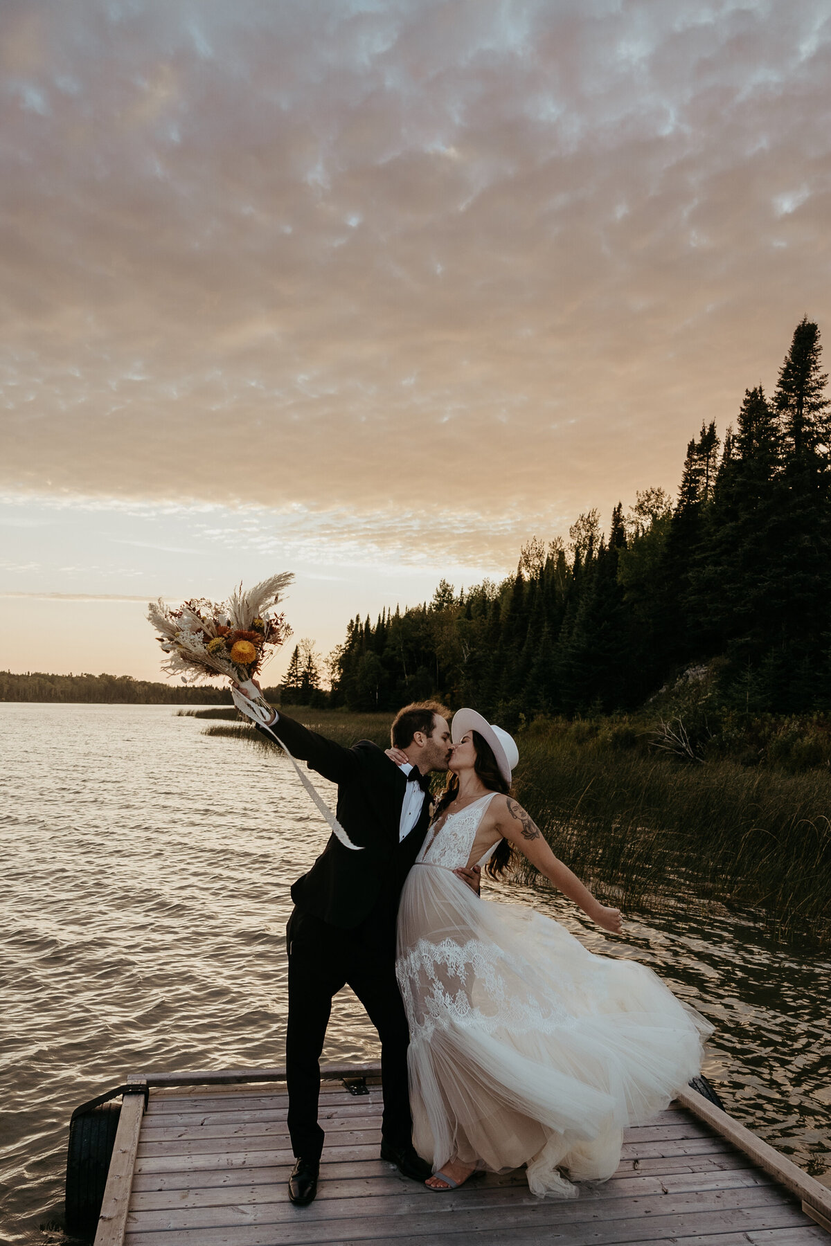 bride and groom kissing on dock by lake