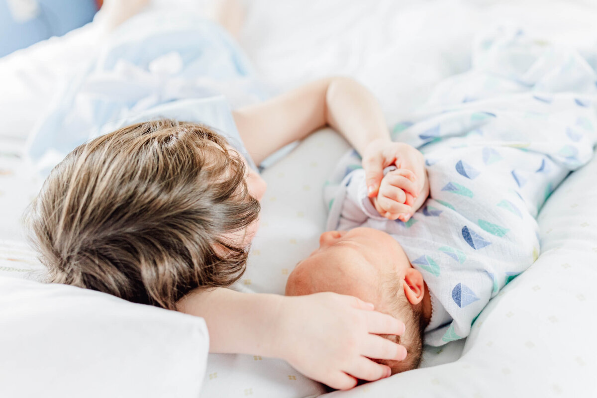 Young girl holds her newborn  brother's hand