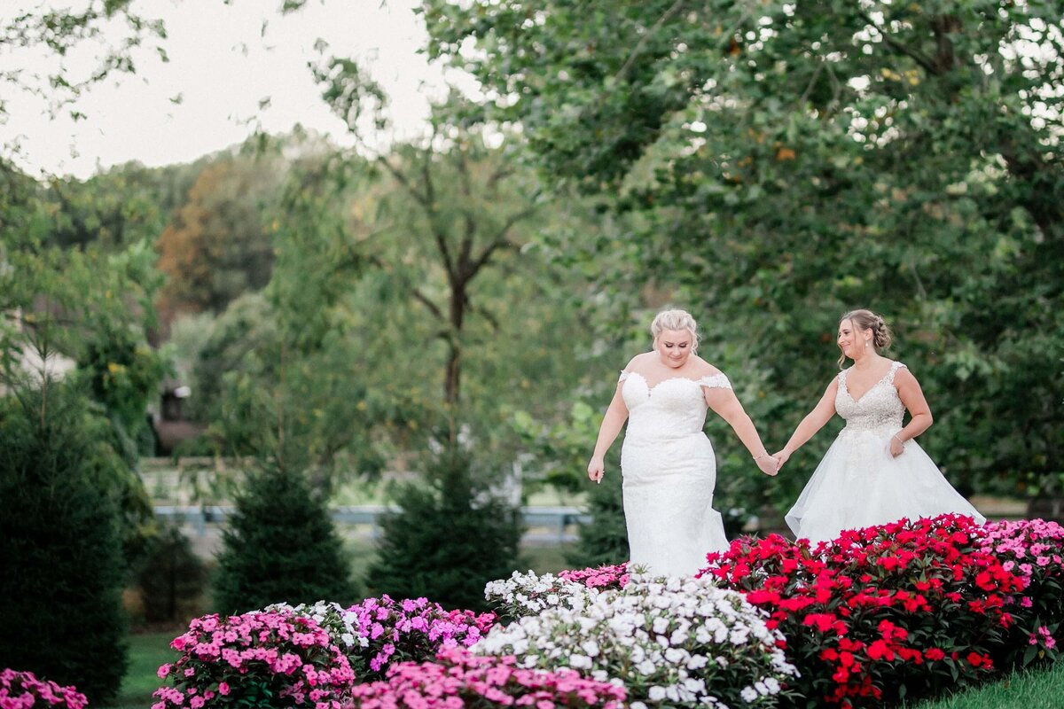 Two brides holding hands in the gardens at Historic Acres