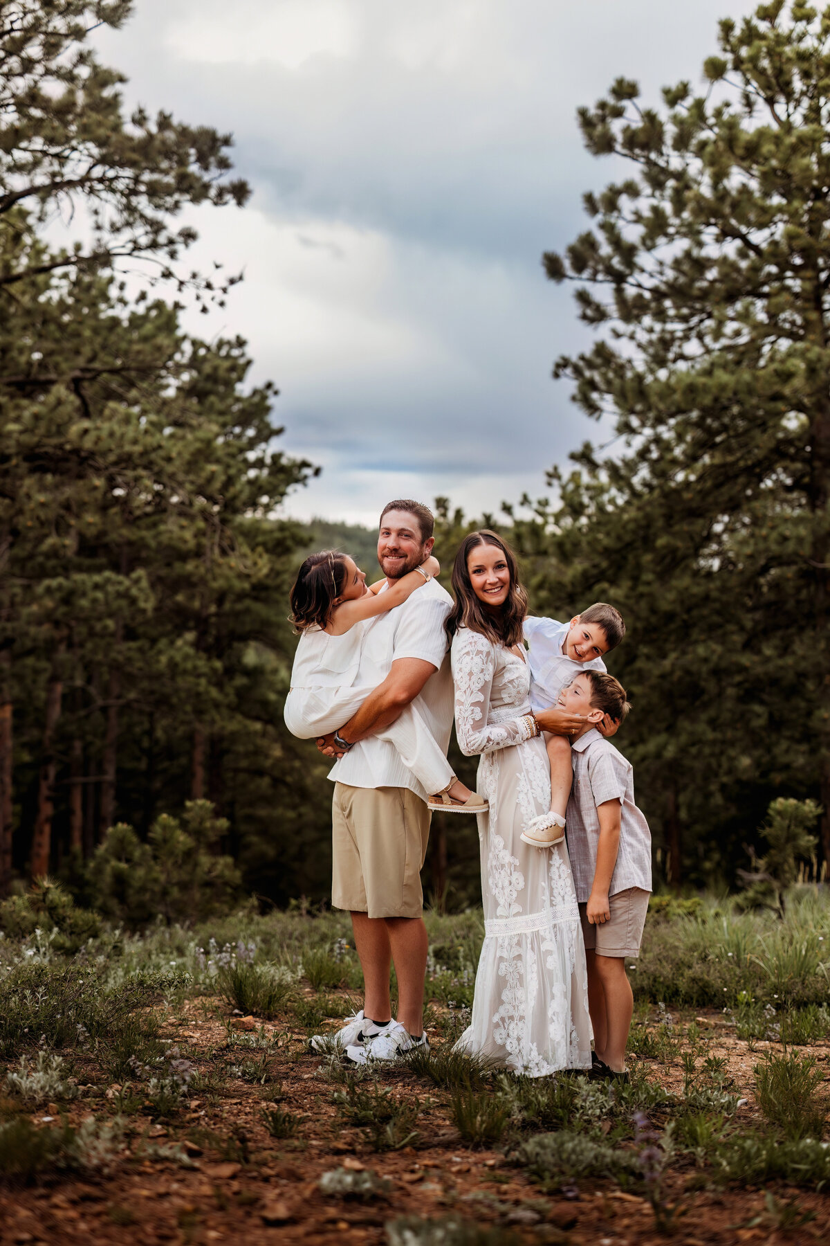 Family of five cuddled close together and being playful in the woods of Colorado for family photos
