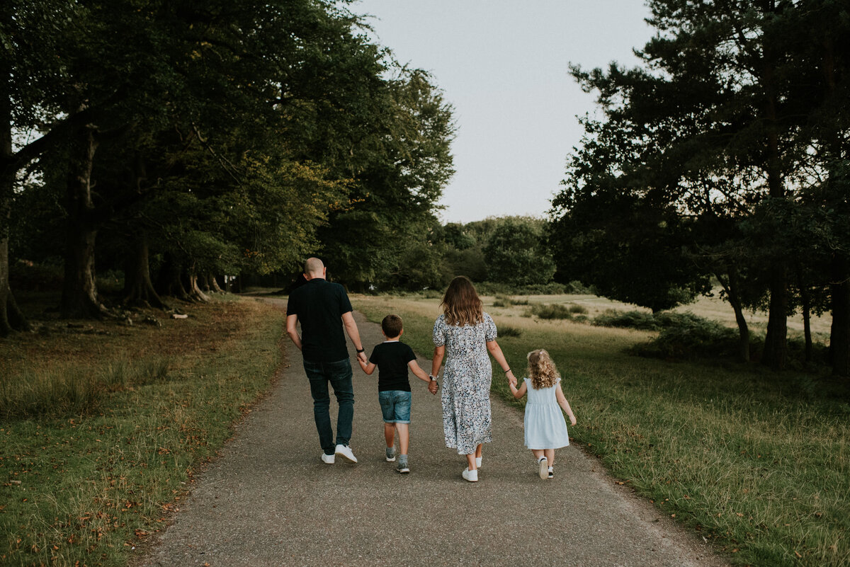 Family hold hands and walking down park path