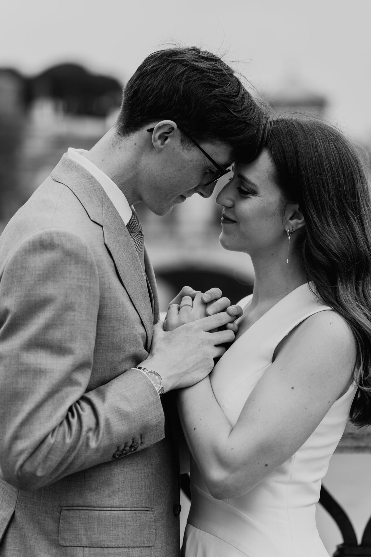 Groom nuzzling bride’s forehead on bridge in Rome.