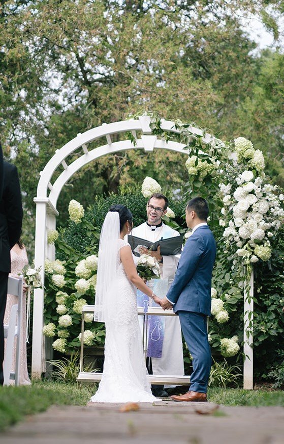 Bride and groom in front of a floral arbor at Oatlands Plantation, Leesburg, VA
