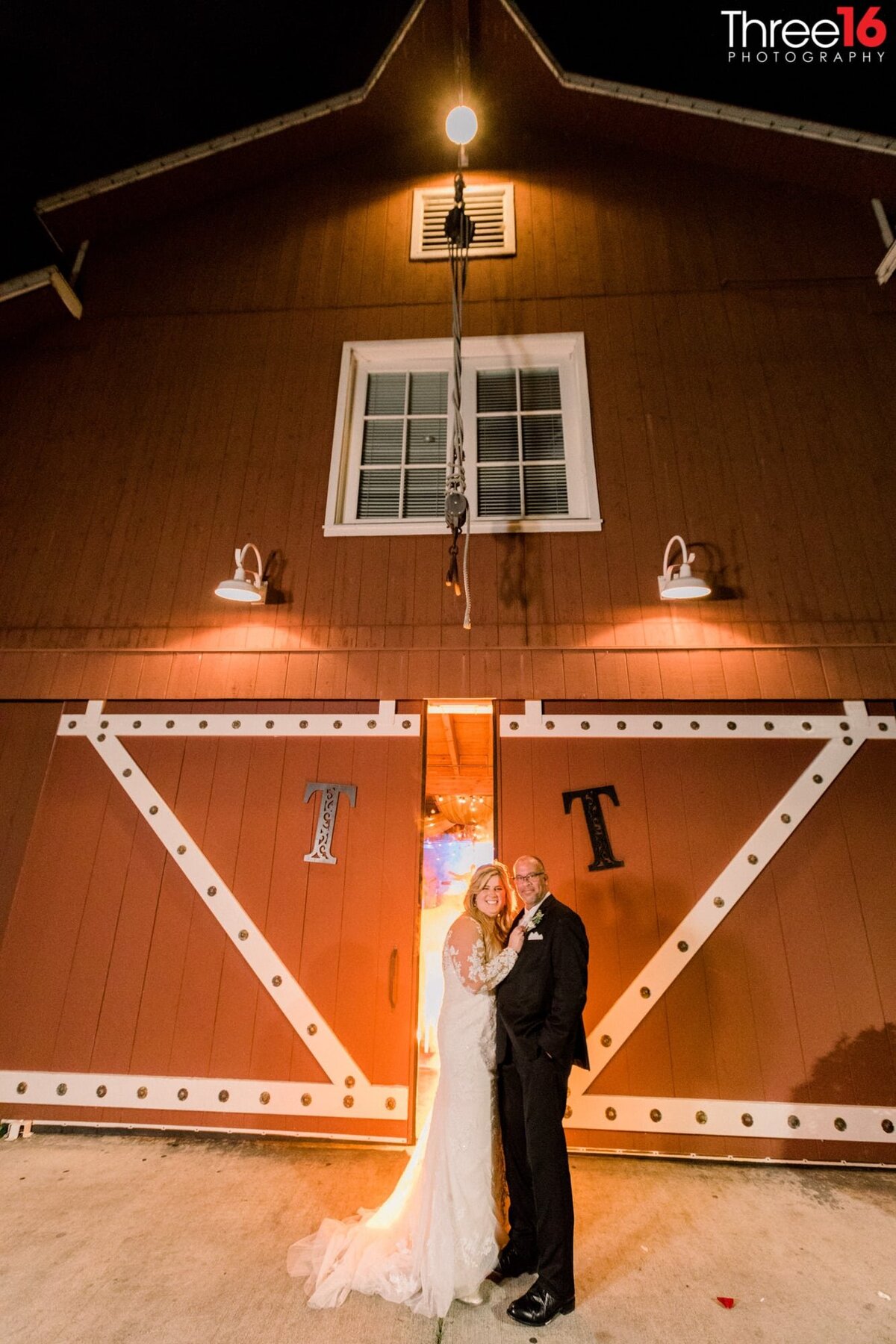 Newly married couple pose in front of barn doors