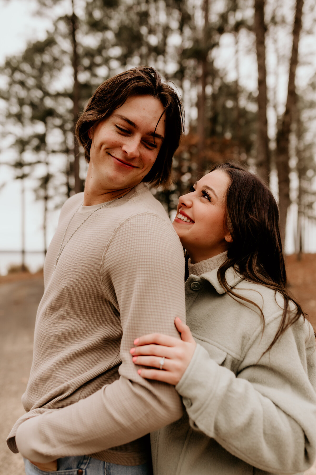 Little rock engagement photographer goes to an adventure session with an engaged couple as the man looks back at the woman and smiles at her as she holds his arm and smiles up at him
