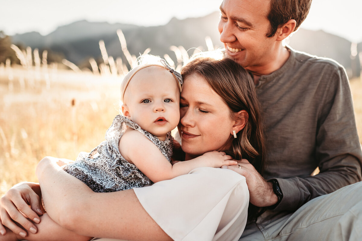 woman laying on her husband and hugging her baby girl