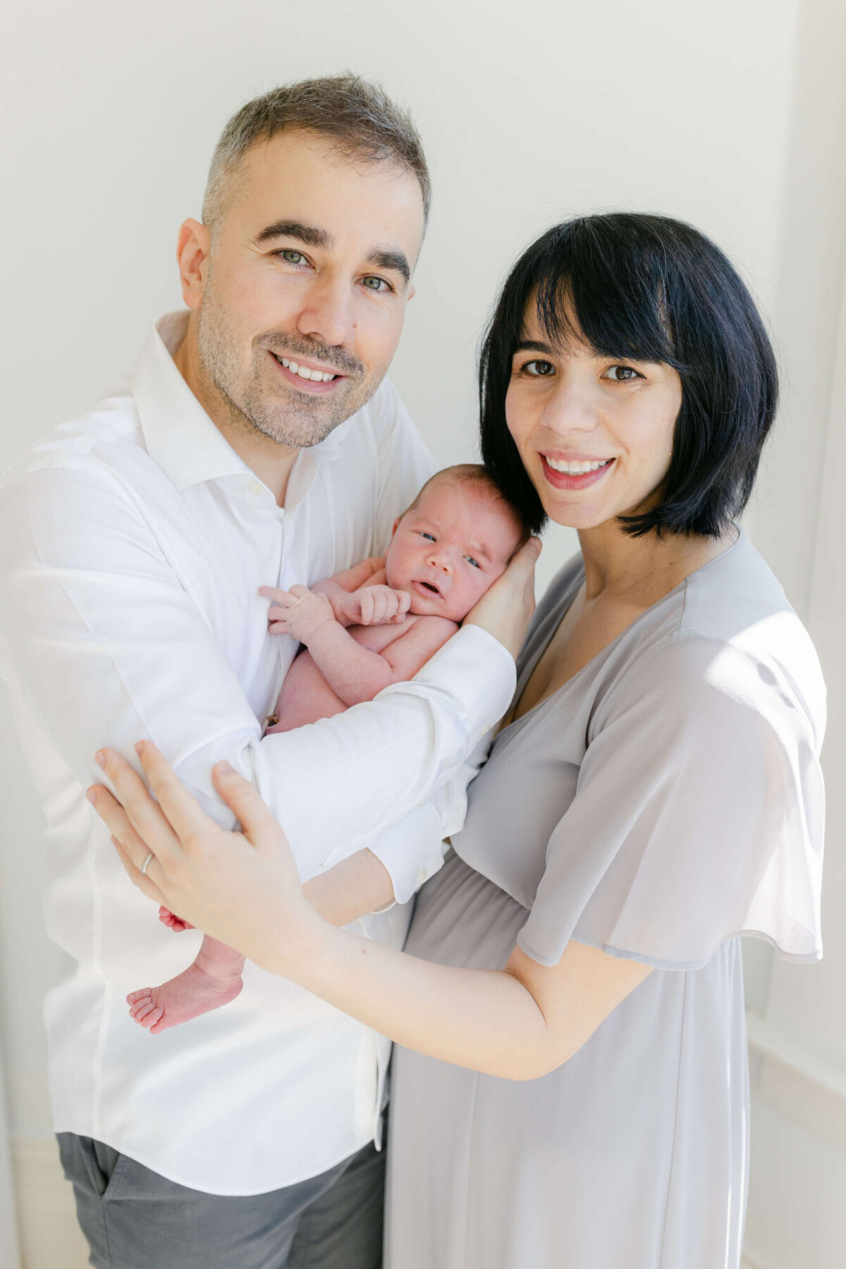 Tender moment of parents and baby in bedroom, Bay Area newborn family photography.