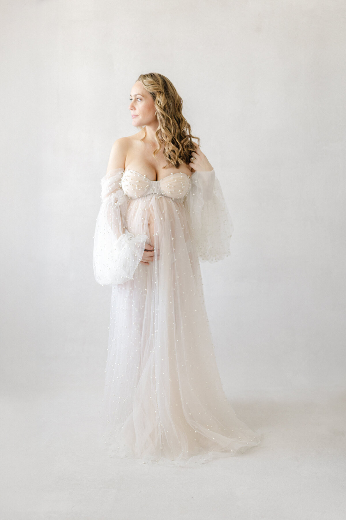 Graceful studio maternity portrait of Katie wearing a luxury tulle gown, captured in natural light in Tampa