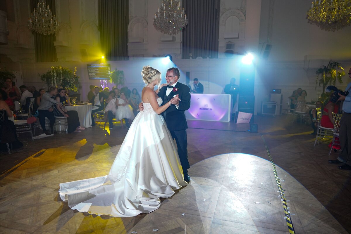 The bride shares a memorable and emotional dance with her father during the wedding reception. This touching moment captures their connection and the joy of celebrating such a special occasion together. The setting is elegant and the atmosphere is filled with love and celebration.