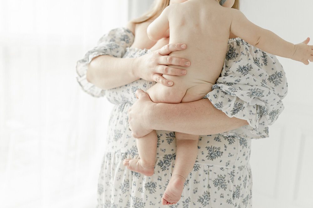 Naked baby butt as he is held by his mother in a blue floral nothing fits but dress in kristie lloyd's nashville photography studio