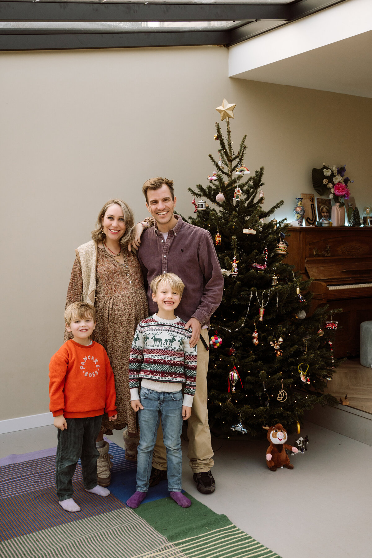 Lifestyle fotoshoot van een gezin dat samen de kerstboom optuigt, met focus op de gezelligheid en de kleine, magische momenten van de feestdagen.