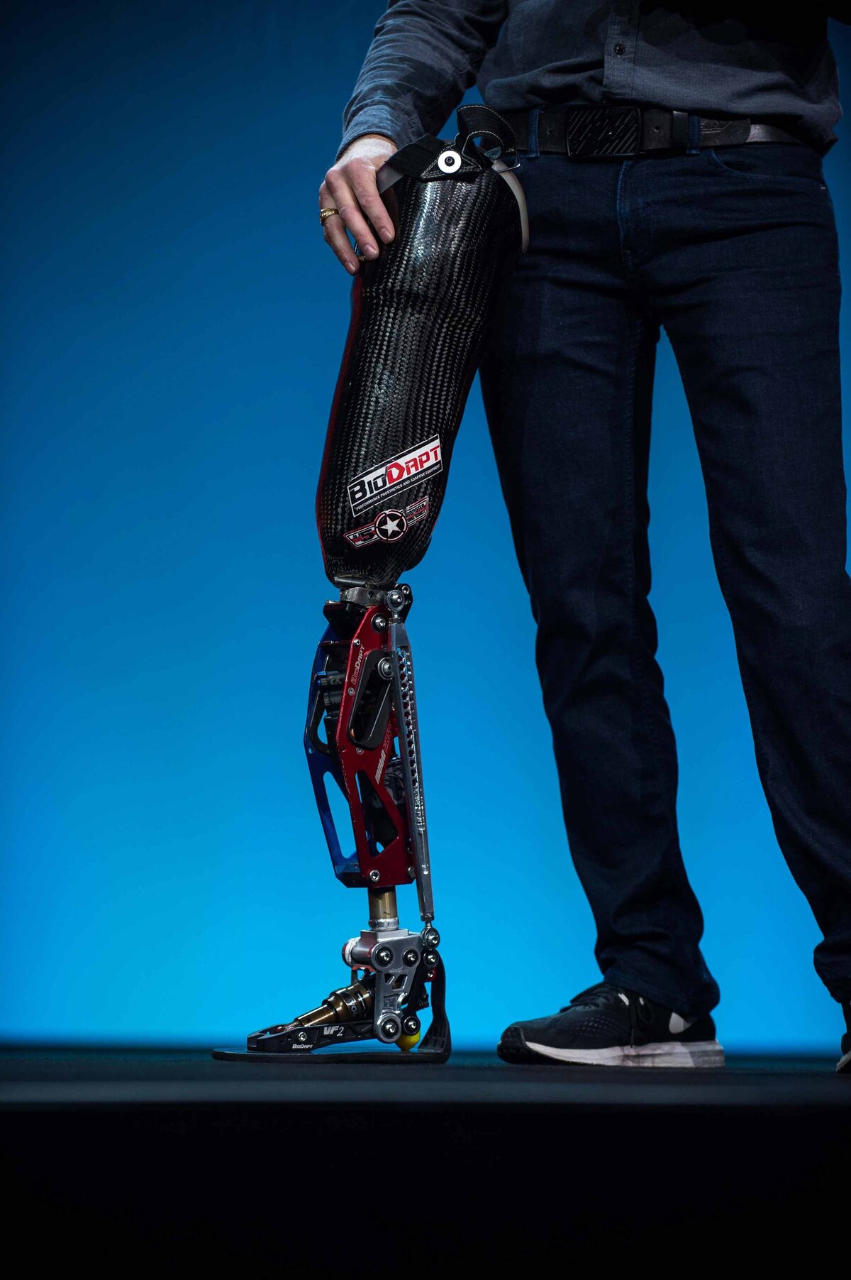 An engineered prosthetic leg with flexible joints and built in shock absorption leans on a mans waist during a presentation