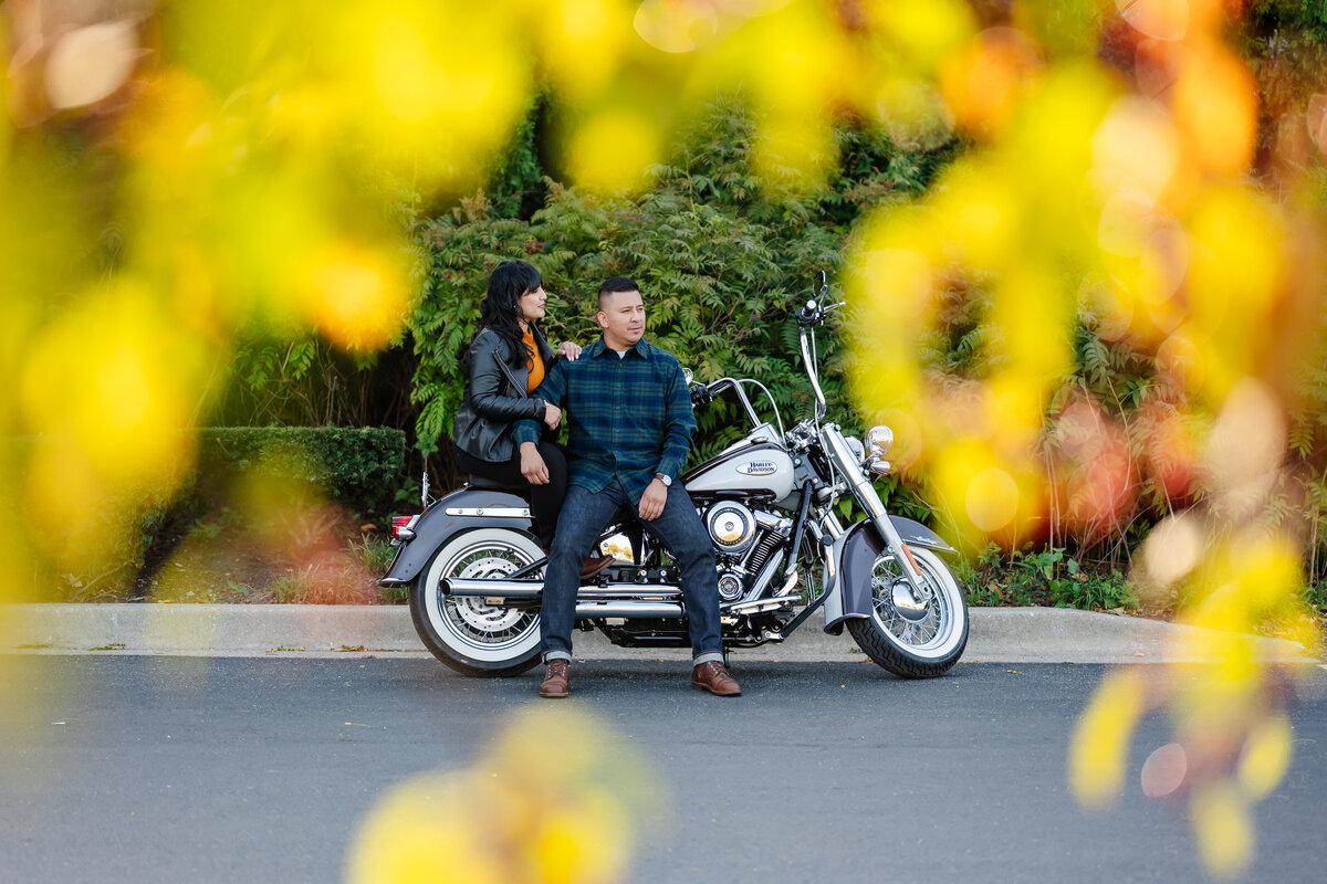 A couple is surrounded by fall colors while on motorcycle 