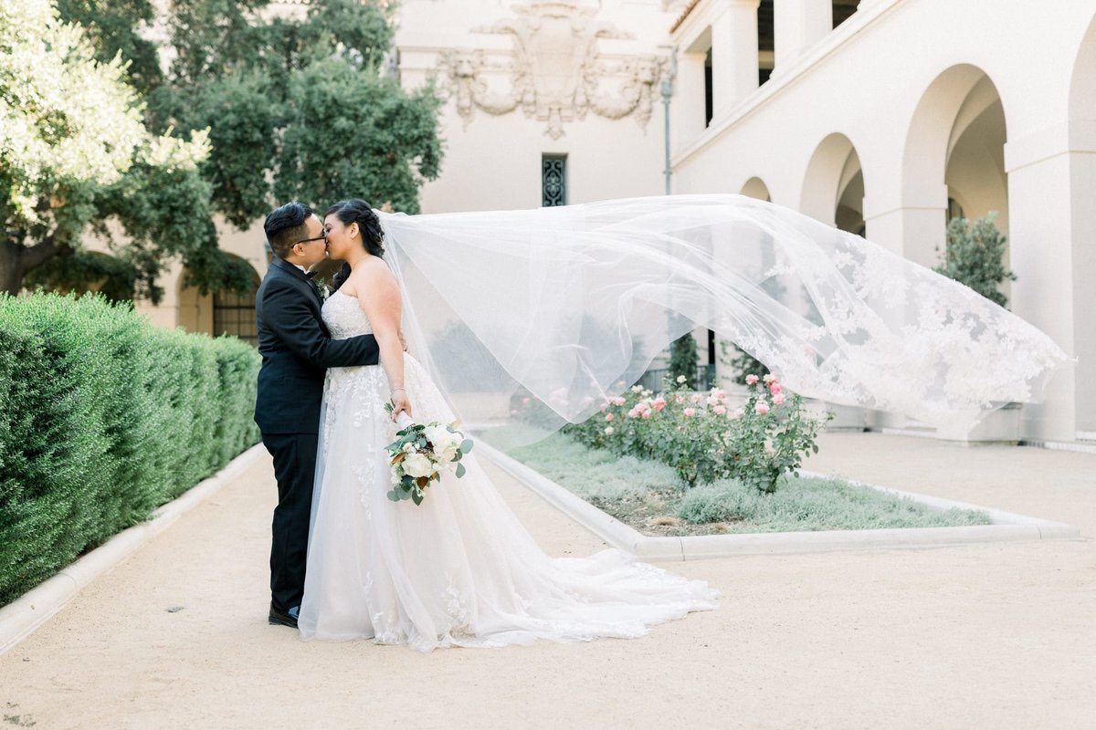 Bride and Groom share an after ceremony kiss as her veil flows in the wind