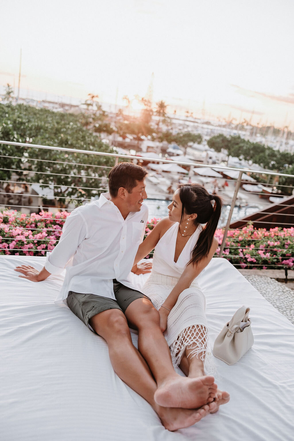 couple sitting on lounge area of the modern with a view of the pool and waikiki boat docks behind them