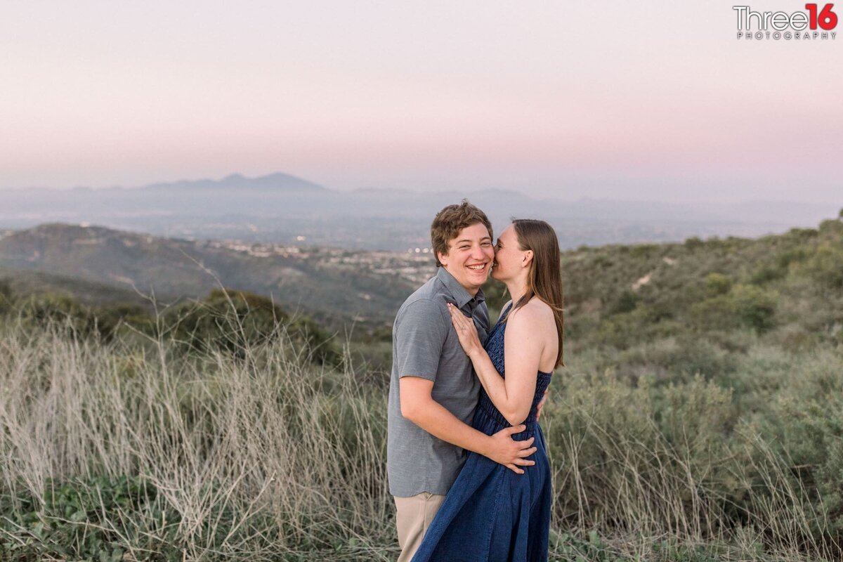 Bride to be whispers into her man's ear during engagement session