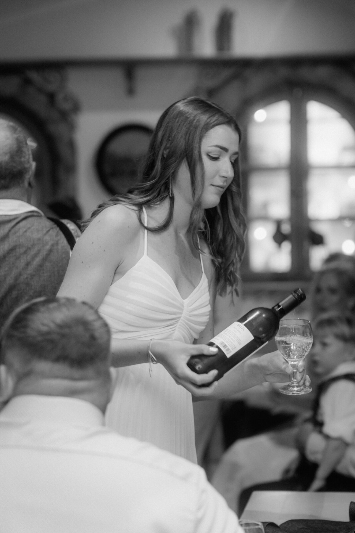 A wedding guests pours some wine in her glas.