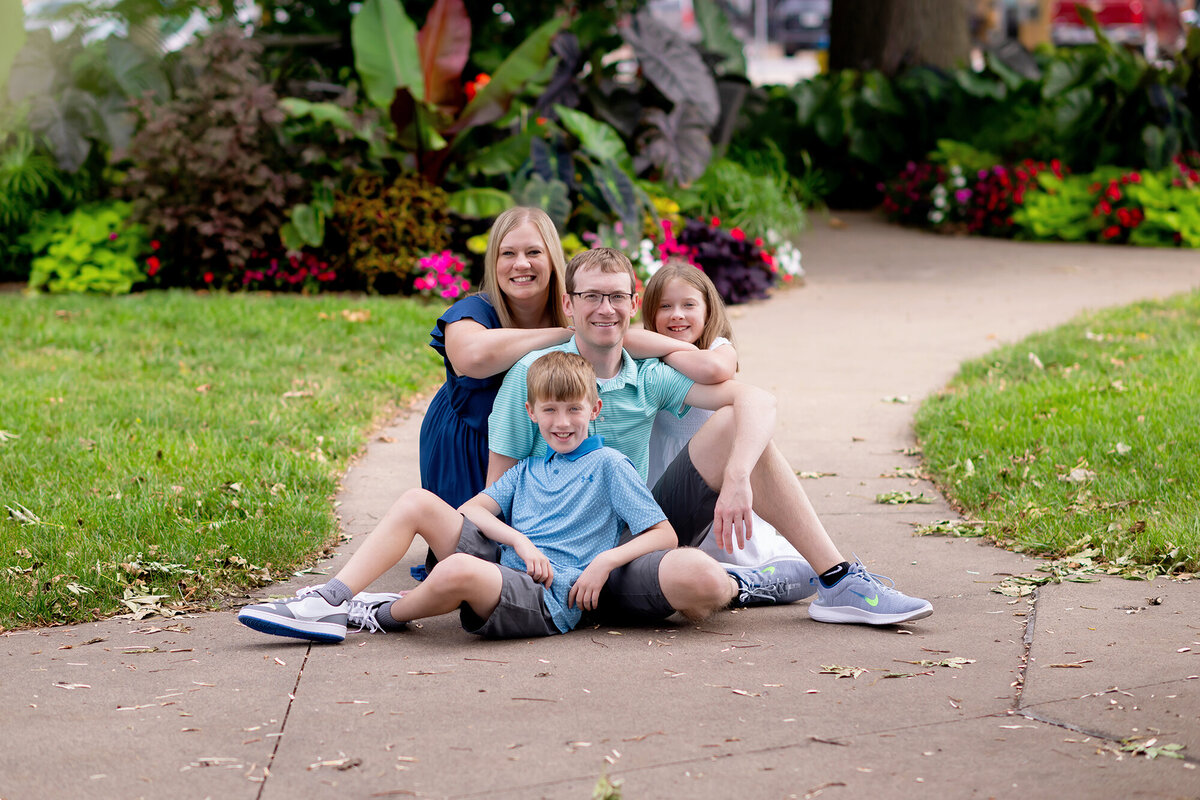 Family of 4 sits on a path through a garden