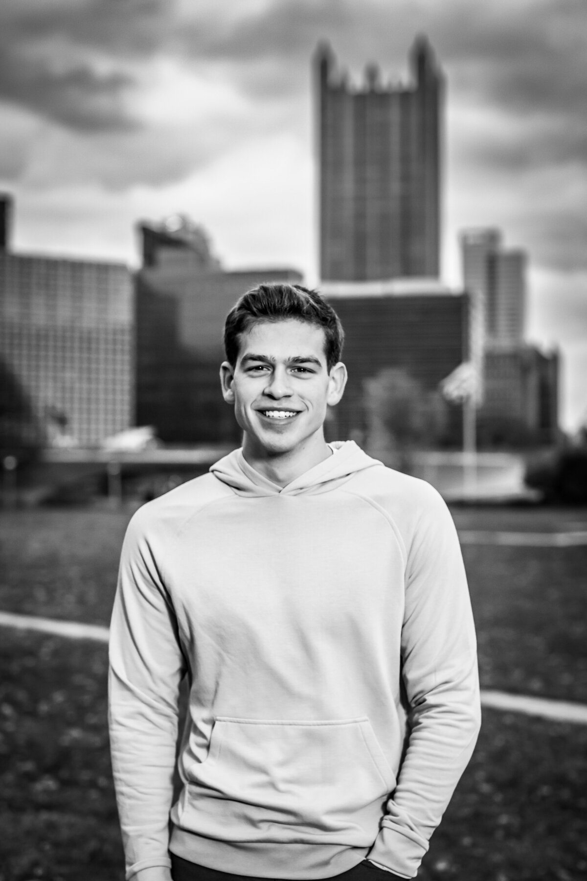a dynamic black and white portrait of a high school senior boy posing in front of the Pittsburgh skyline from Point State Park.