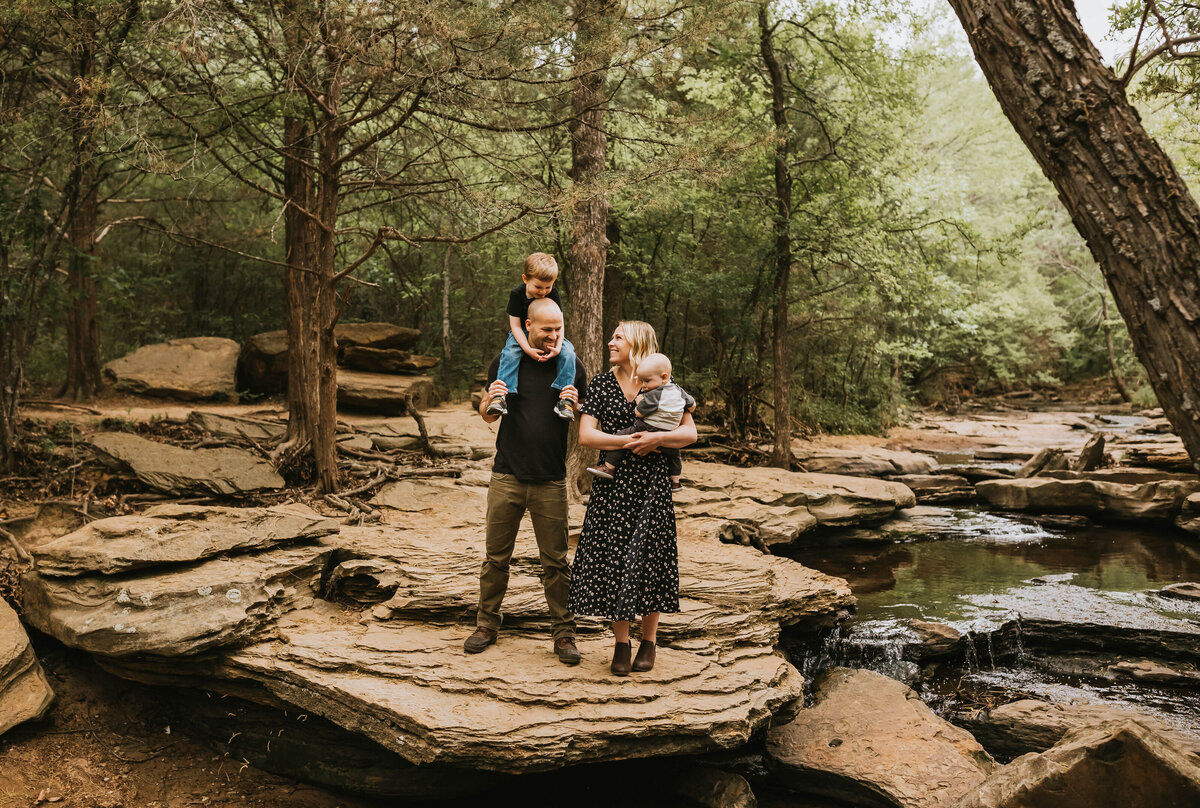 Cute family standing on a rock formation in a creek wearing coordinated clothing