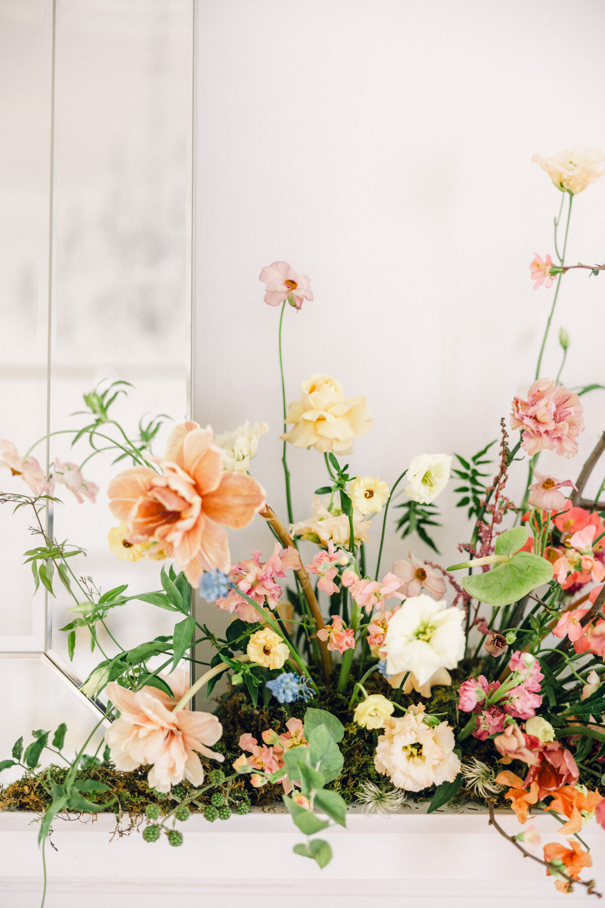Colorful flower arrangement against white wall.