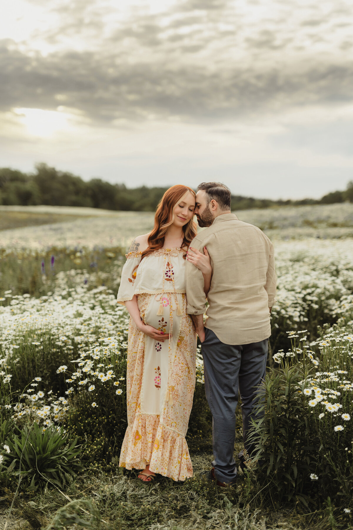 Pregnant mother in wildflower field with partner during golden hour maternity photos in Greensboro NC