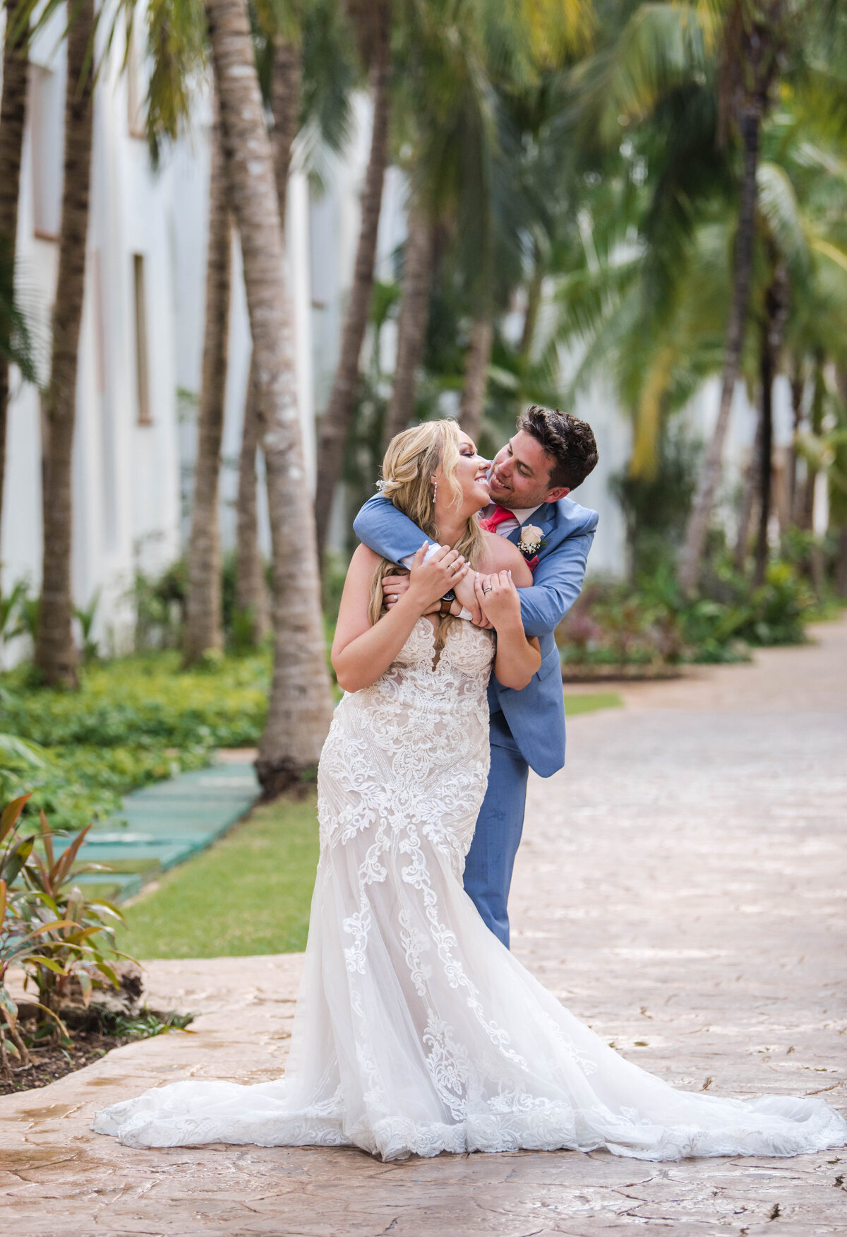 a bride and groom on a palm tree lined path