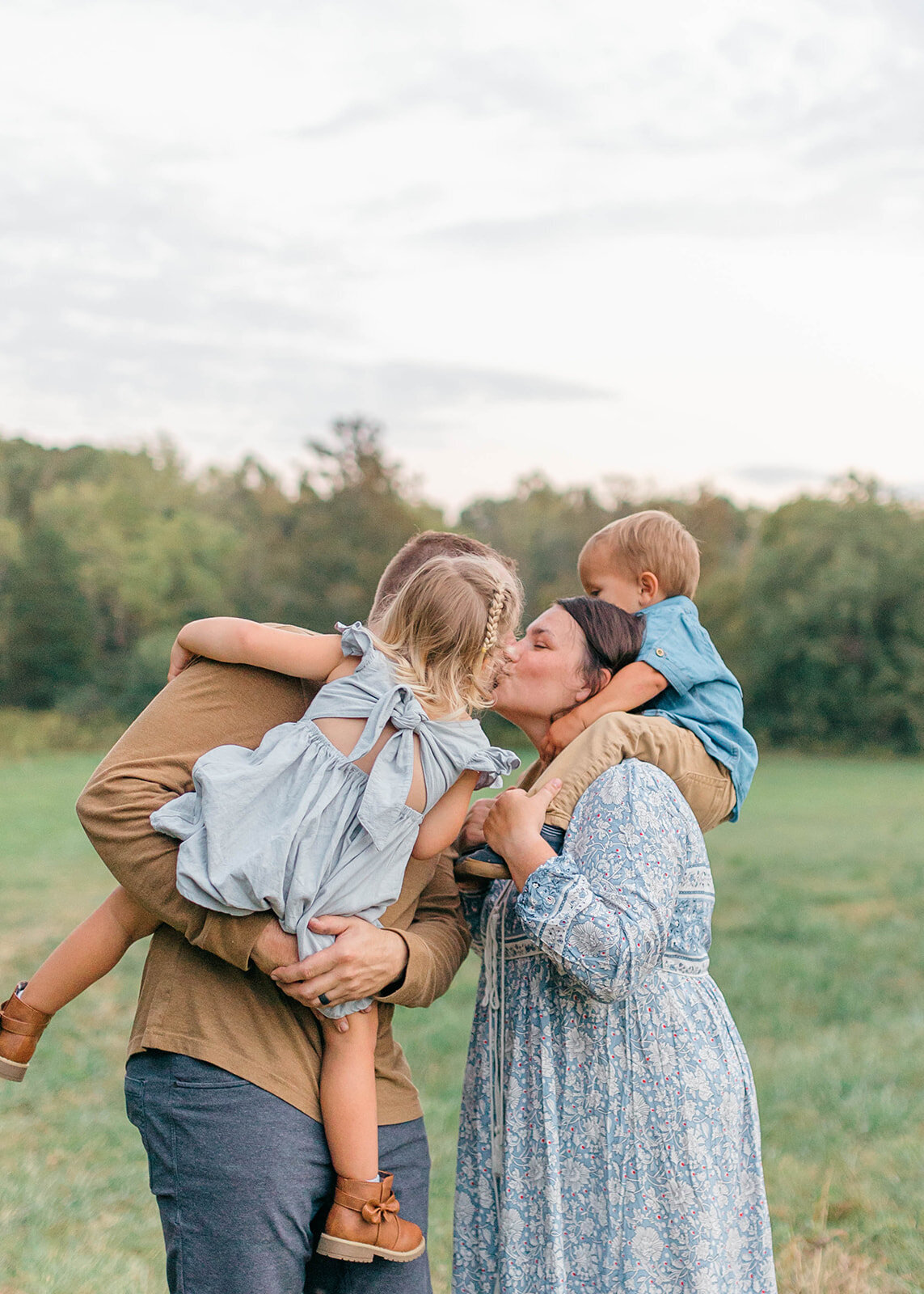 Mom and dad kissing while carrying kids