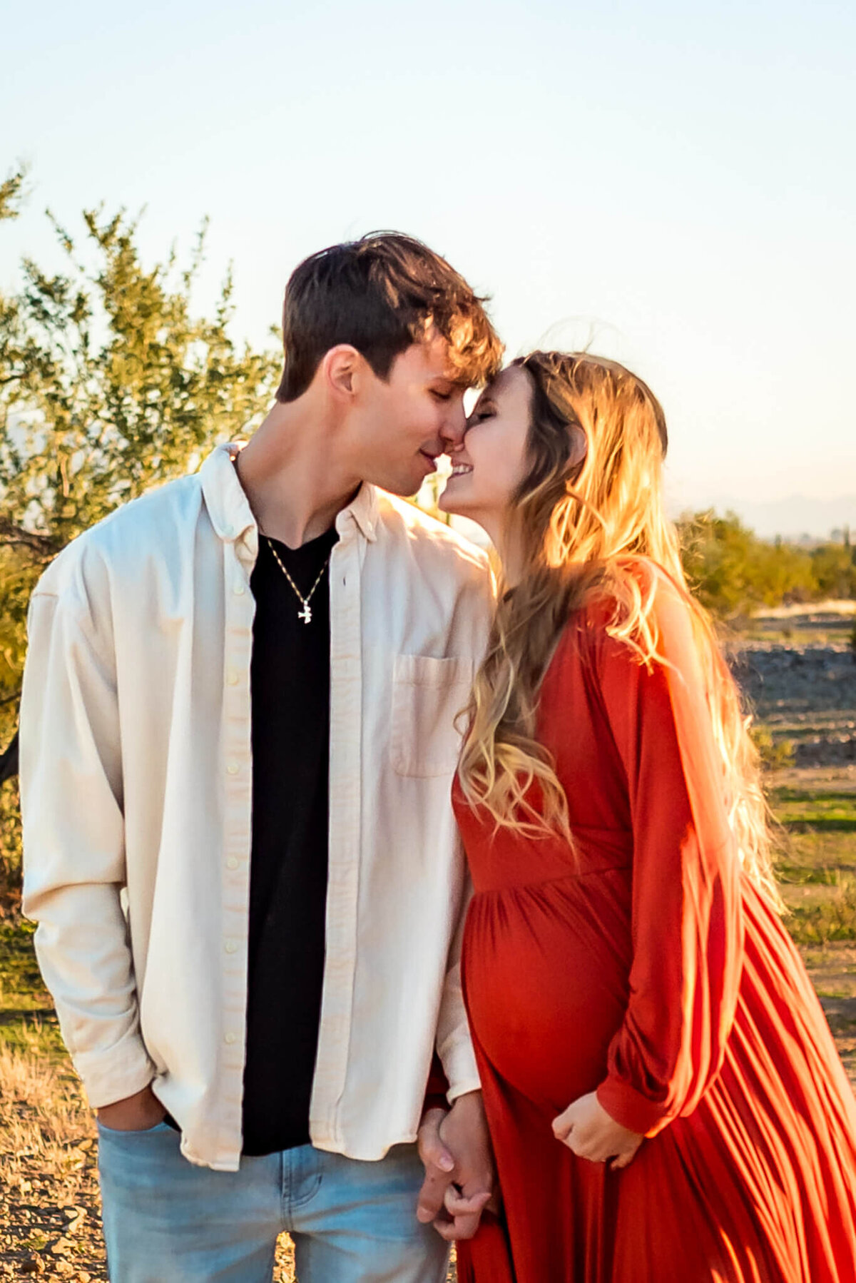 Expecting parents photographed just before a gentle kiss.