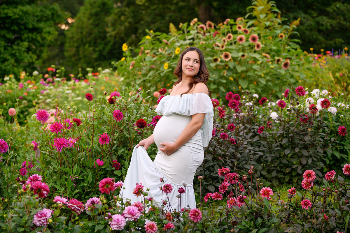 pregnant lady wearing a mint maternity dress outdoors in a flower garden in Burlington, ON