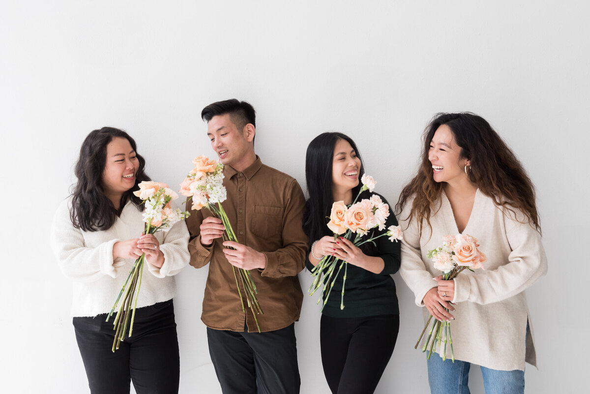 Seattle floral design team smiles and chats with each other while holding flowers