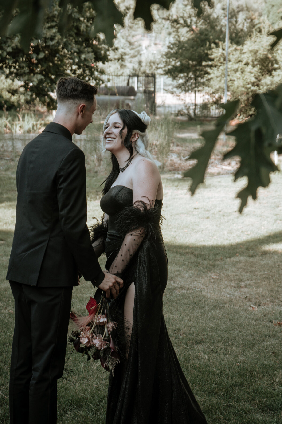 Bride and groom in mountains of Oak Glen, California having a first look and holding hands in their goth attire and trendy gloves