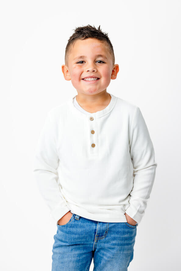 Boy in white puts hands in pockets during his session at Angela Marie Media.