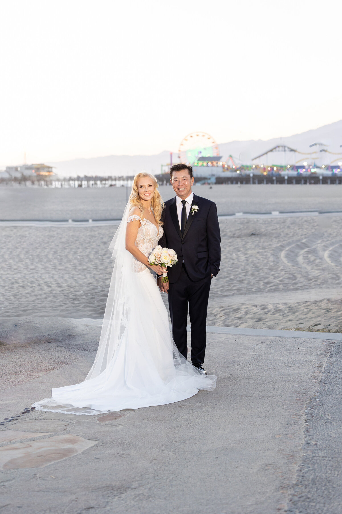 A bride and groom holding hands and standing near a beach