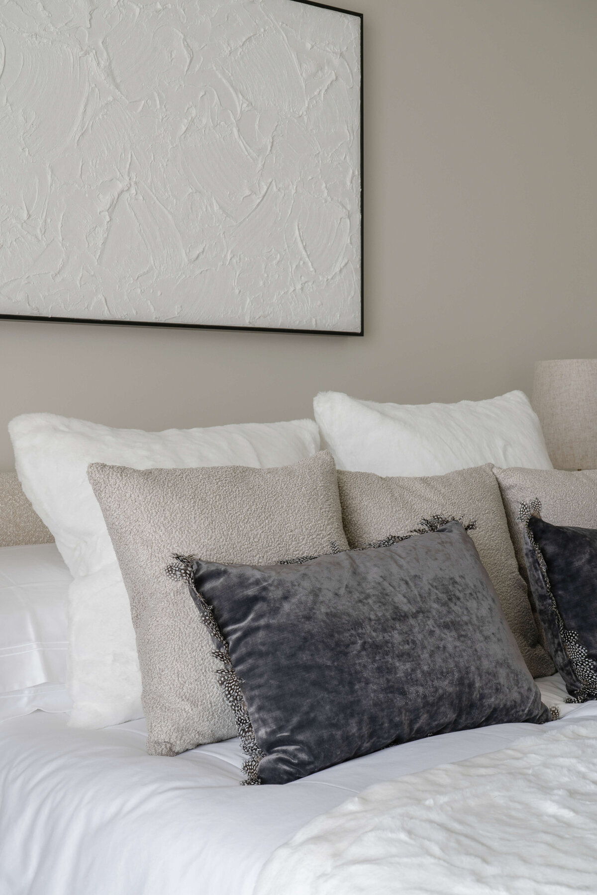 Soft neutral pillows arranged on a white bed in a cool and airy guest bedroom.