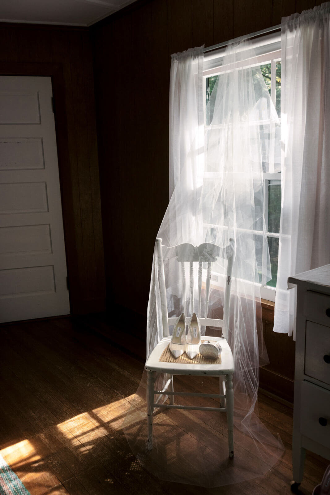 The bride's shoes and pouch are placed on a white chair covered by a white veil inside a room at The Ausable Club, New York.