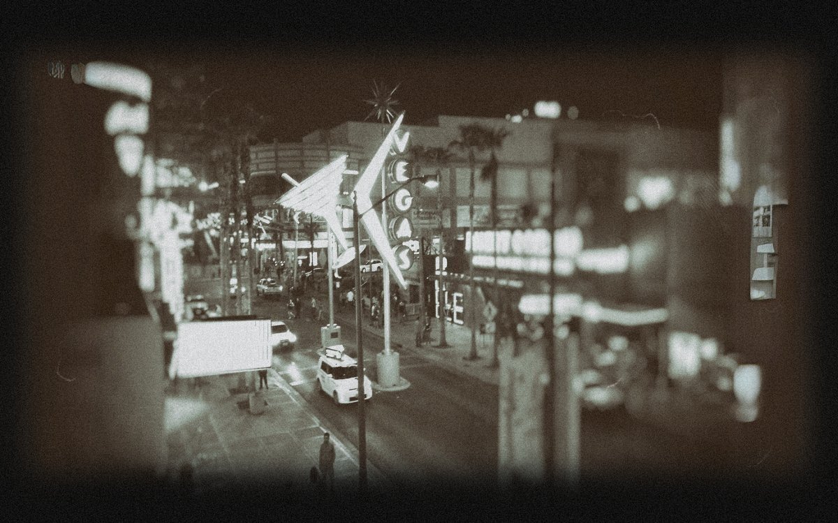 Vintage-style nighttime photo of the iconic “Vegas” sign on Fremont Street with glowing neon lights, taxi cabs, and palm trees, capturing the nostalgic energy of downtown Las Vegas.