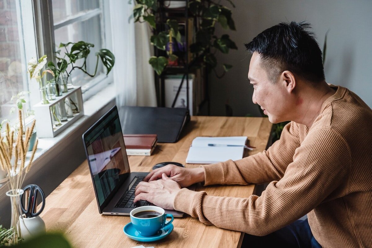 Man of Asian descent in a brown waffle-weave shirt working on a laptop. Photo by Annushka Ahuja via Pexels.