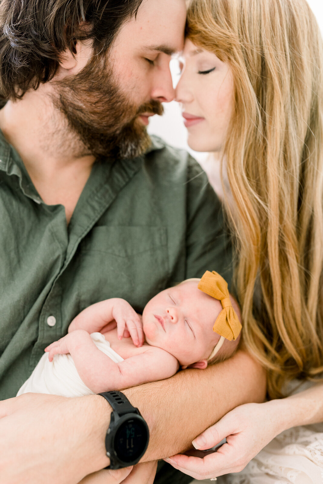 Father holds baby girls while snuggling his wife