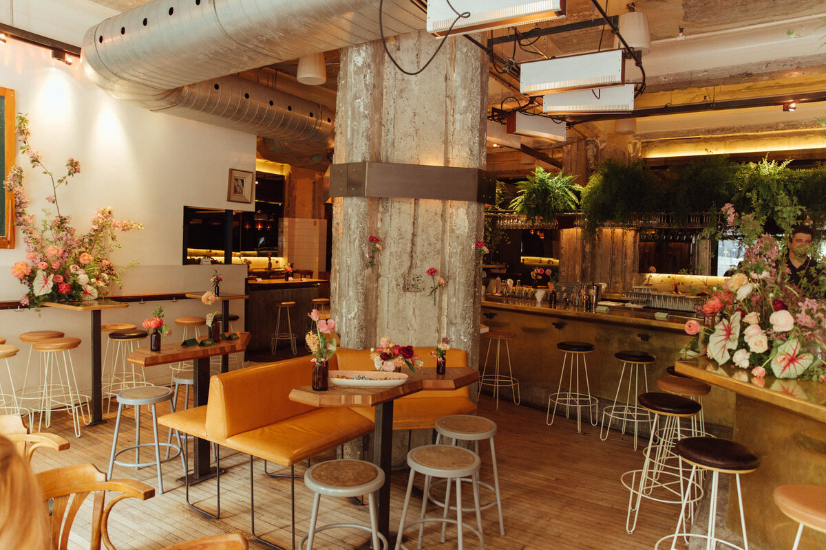 Industrial chic decor for a wedding reception at Bar Furco featuring colourful flower arrangements.